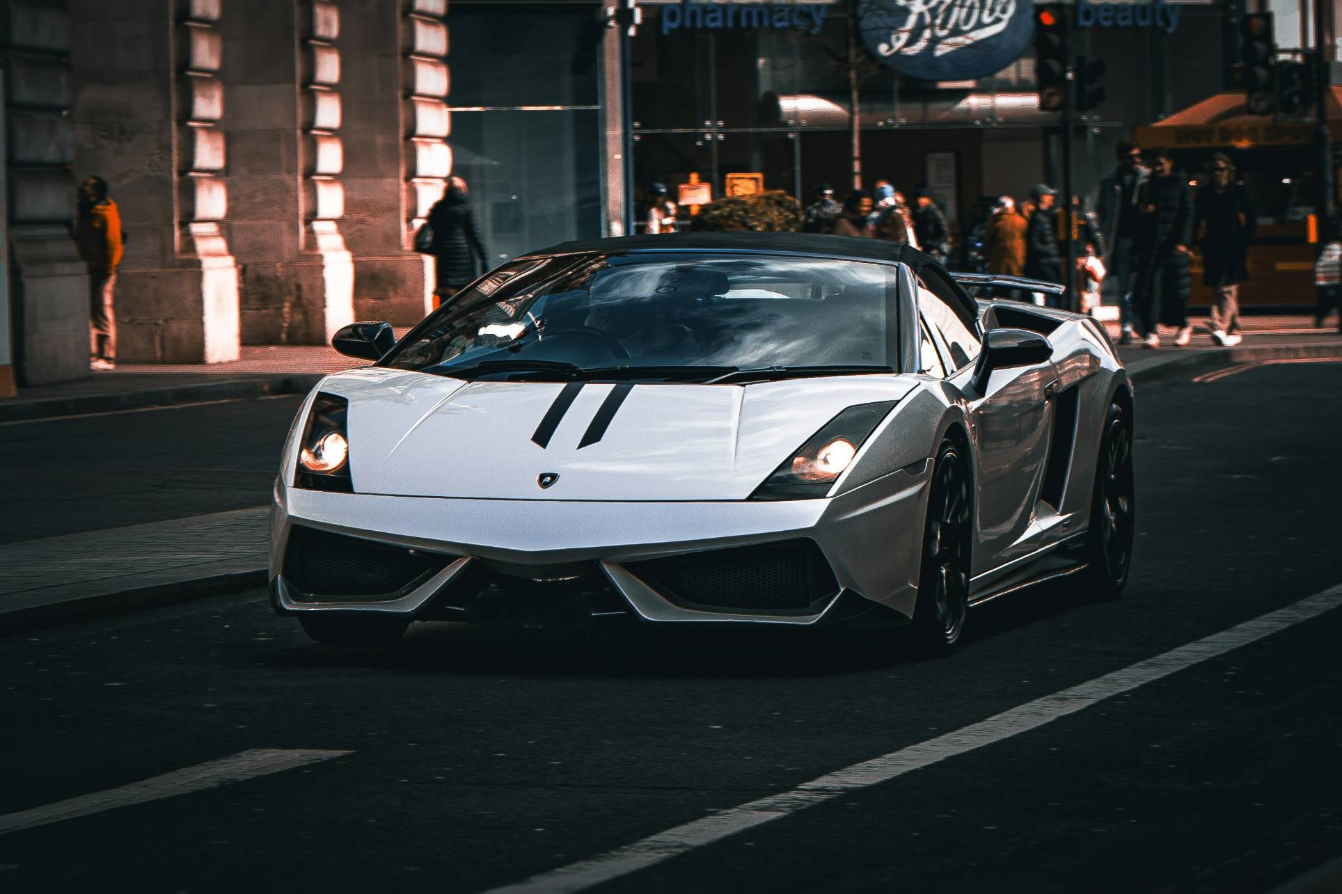 A white lamborghini drives down the street.