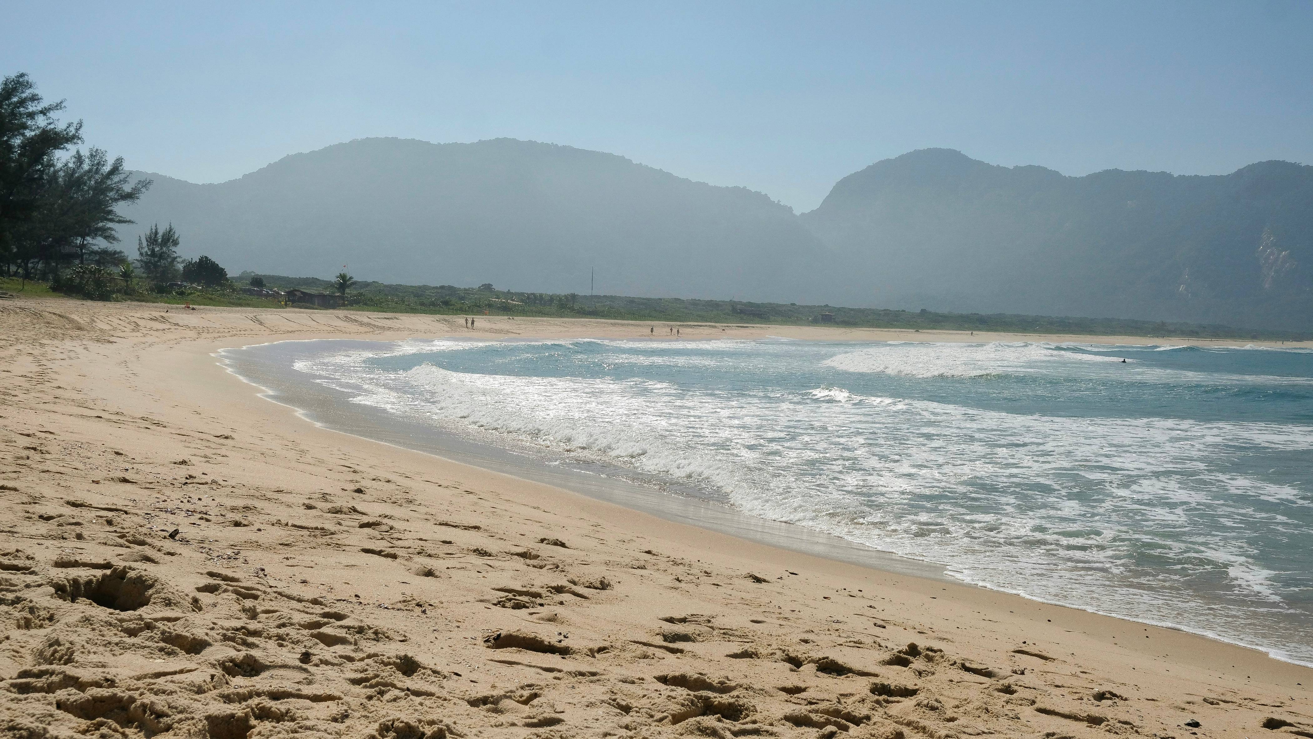 a sandy beach with mountains in the background