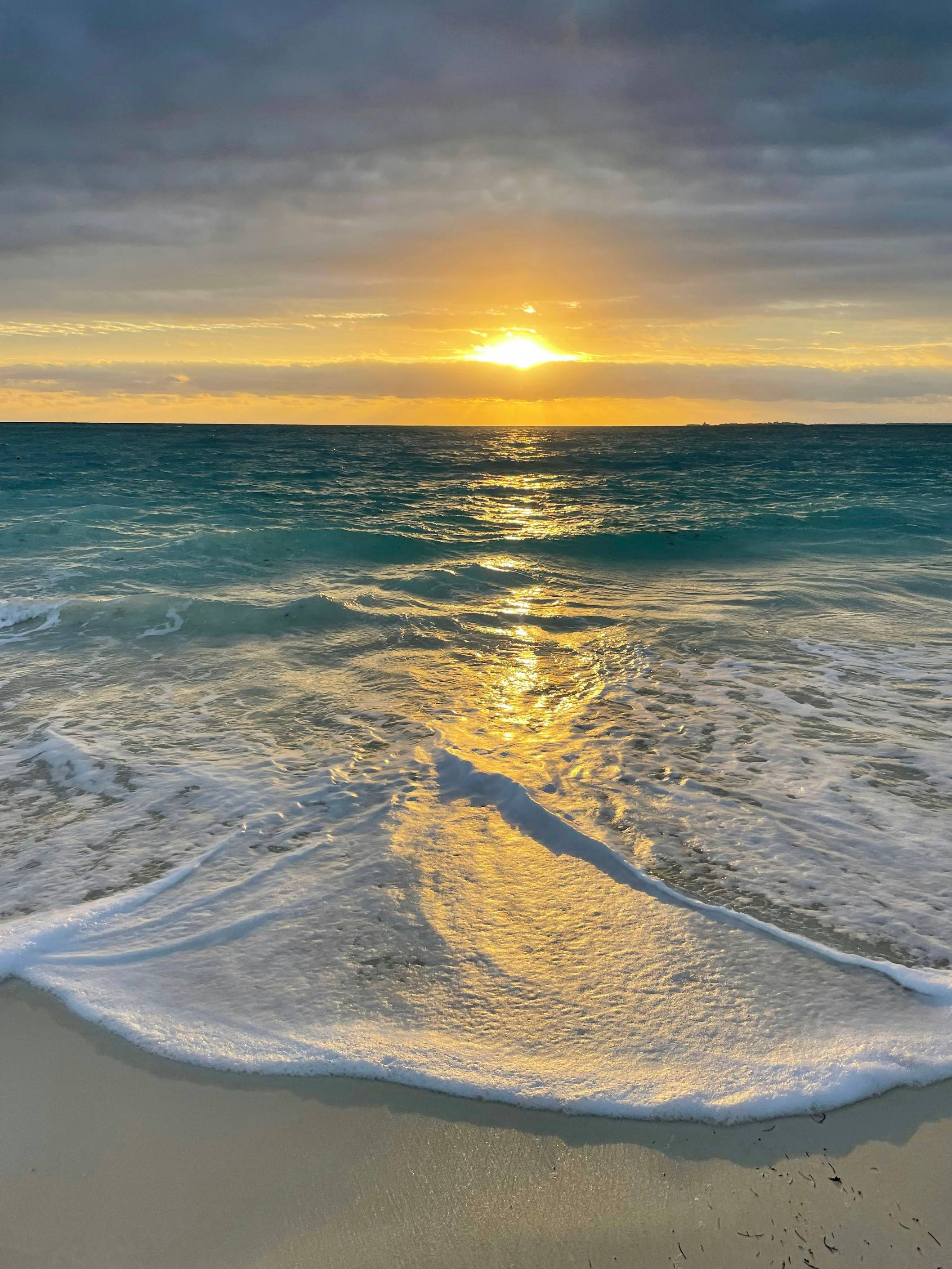 the sun is setting over the ocean on the beach
