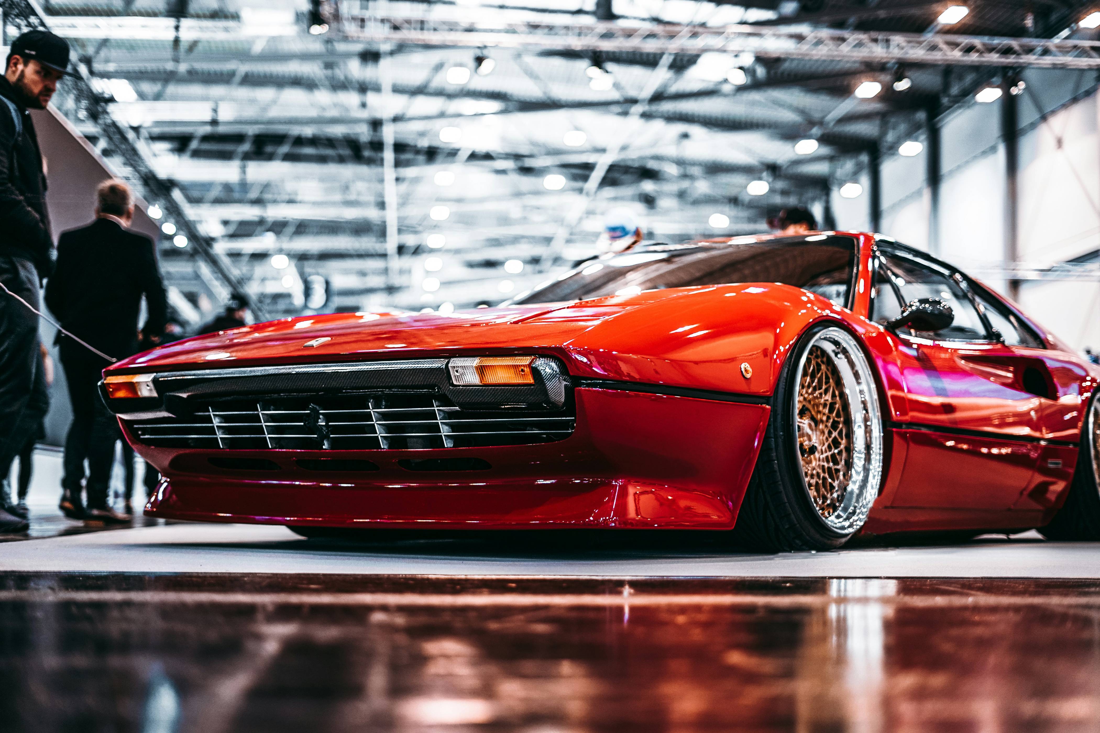 man standing beside red coupe